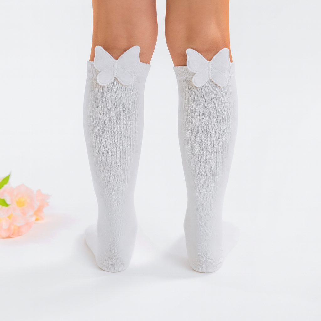 White knee-high socks with bow details worn by a person on a light gray background.