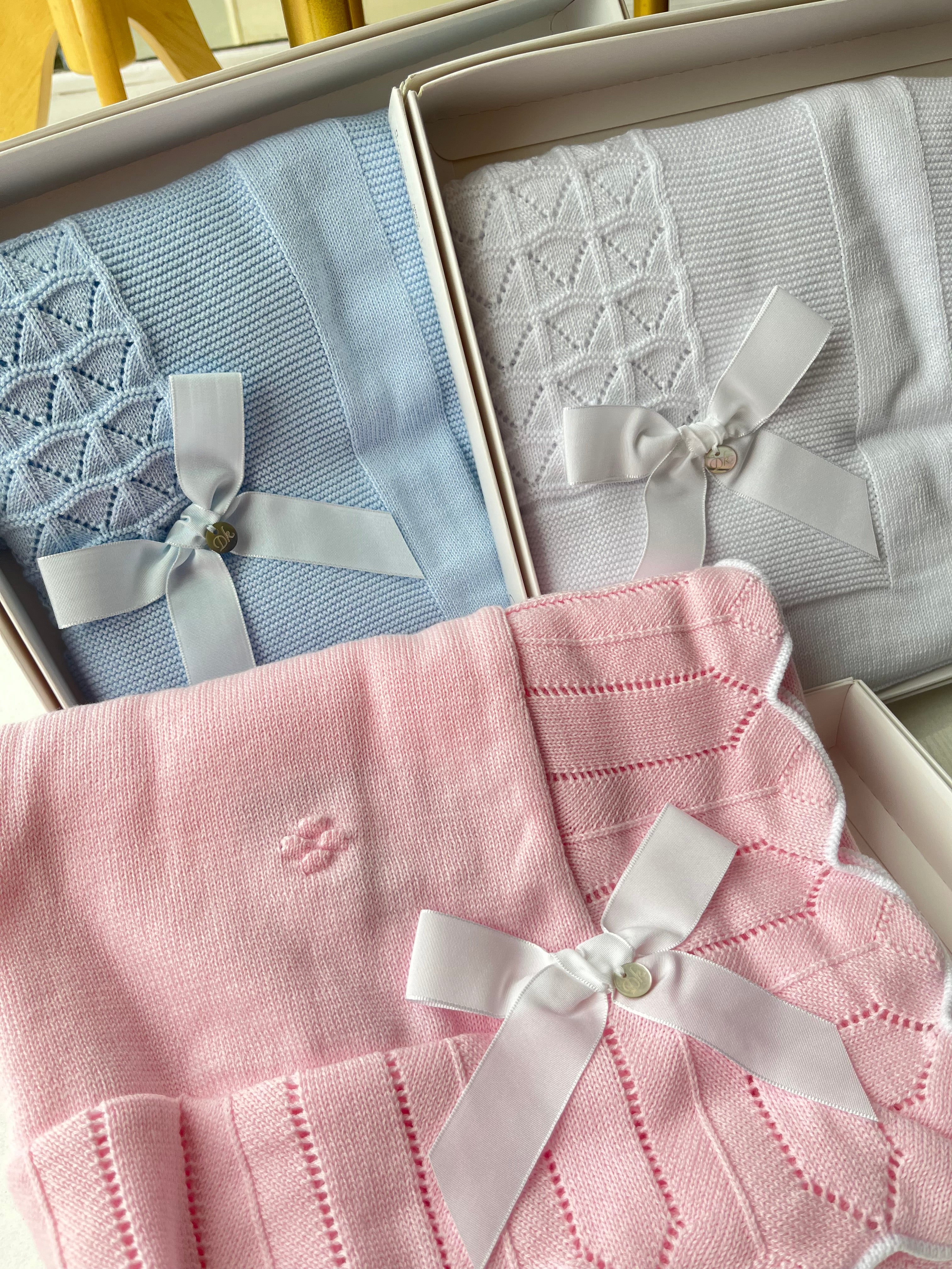 Soft knit baby blanket from Dr. Kid in pink, white, or blue. Features elegant bow detail and 100% cotton comfort. A perfect newborn gift idea. 