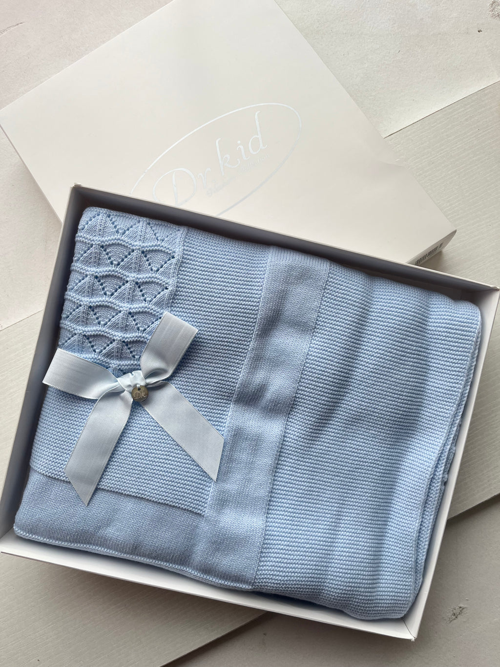 Wrapped in love, tied with a bow. The Dr. Kid knit blanket is here – soft, gift-ready, and simply beautiful.